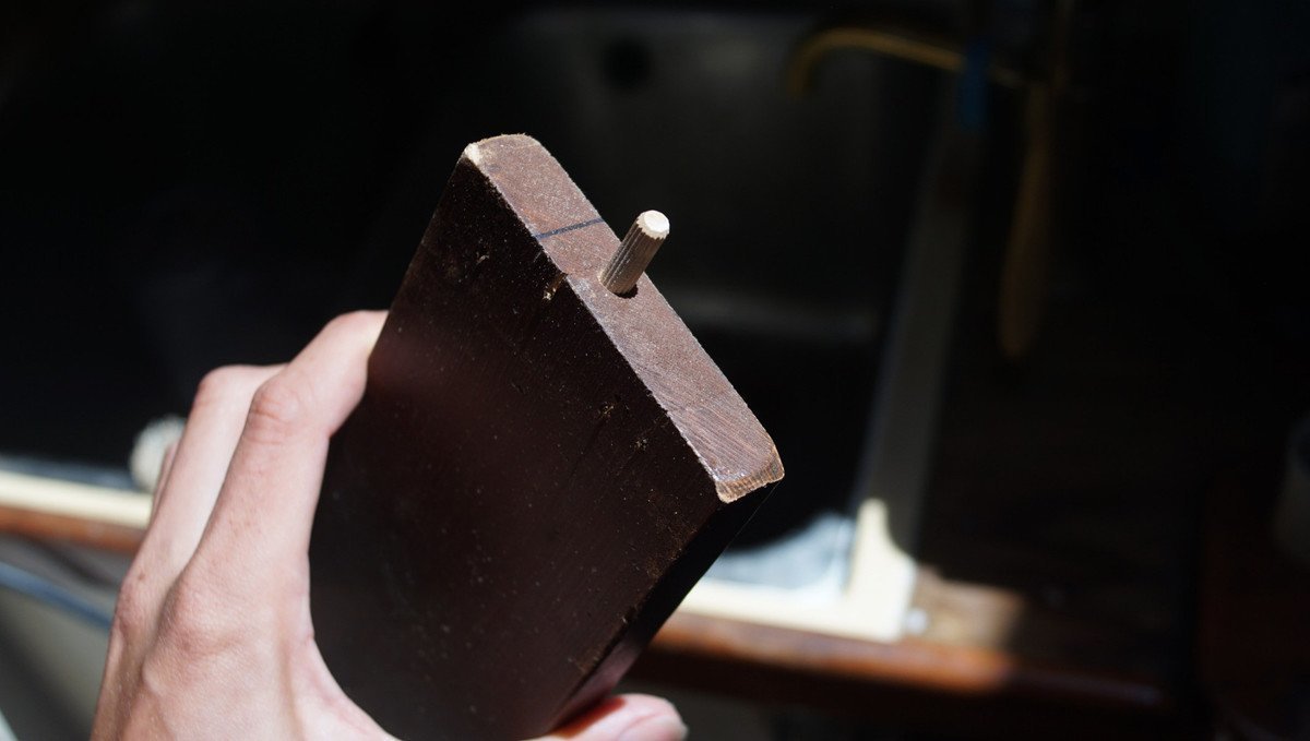 A photo of a hand holding a piece of wood with a dowel it in