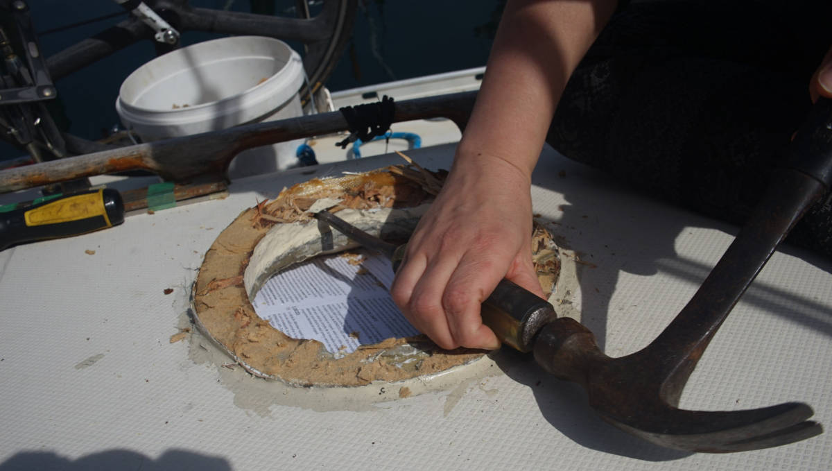 rek taking the wooden deck ring apart with a chisel and hammer