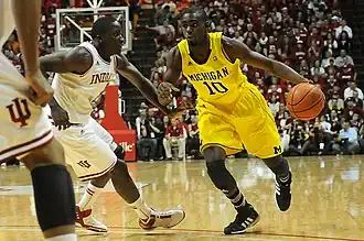 Player dribbling, guarded by two players in white uniforms