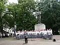 The historian Eero Medijainen speaking on Estonian Independence Day in front of the Tartu War of Independence Monument, behind him the female choir Emajõe Laulikud [et], August 20, 2012