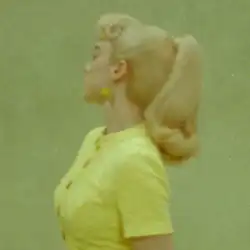 Cover art for "What Was I Made For?": a side-view photo of Billie Eilish in a yellow shirt and with a Barbie-inspired ponytail