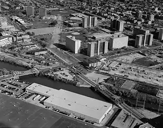 A black-and-white photograph of a neighborhood; it is taken from an aerial point of view.