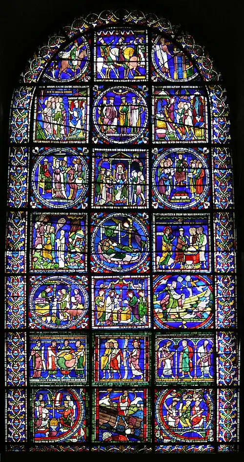 Round-topped window with ancient glass, predominantly blue.