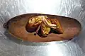 Corviche, dough of grated green plantain, peanuts, and a vegetable sofrito, filled with pieces of fish, and then fried.