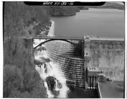 View of spillway looking upstream perpendicular to dam axis. White water flowing down spillway and calm water upstream from the dam.