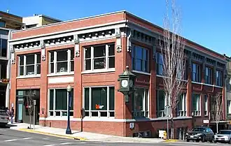 A historic red brick building with an antique clock hanging on the corner