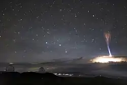 Photograph of a distant gigantic jet atop a thunderstorm
