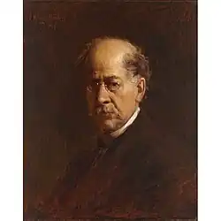 A head and shoulders portrait of a sixty something man, wearing glasses, facing to the left