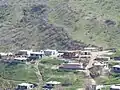 Overview of Kovli village with houses on a green hillside surrounded by open land