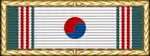White ribbon with vertical green and red stripes on its edges and a red and blue circle in the middle