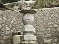 A closeup on the same Buddhist grave's tombstone, showing a sculpted image of Gautama Buddha in meditation