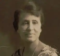 Photograph of a black woman in a sleeveless sheath wearing pearls.