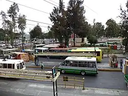 The bus terminal outside Tasqueña station, with several minibuses parked. The area also features some retailers.