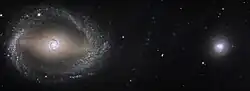 A larger spiral galaxy on left and smaller rounder galaxy on right in star field.