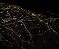 Nighttime aerial view of much of the density of Nassau County, from the west-northwest; Hempstead is in the center, with roads projecting out in various directions; bridges to Jones Beach Island are at the upper right. The Grand Central Parkway–Cross Island Parkway interchange, barely visible at the lower left, is just outside the county, within Queens.