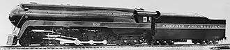 A black-and-white photo of a streamlined steam locomotive with its tender