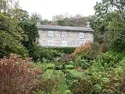 a garden with hedges and shrubs overlooked by a house