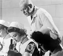 student nurses, in traditional garb, studying in a laboratory with instructor nearby