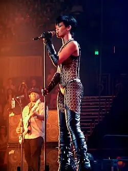 Rihanna with a bob cut performing in into a microphone on a stage