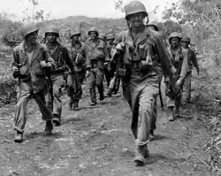 two columns of American soldiers marching toward right of camera