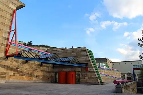 Contradiction (in this case, the mix between monumental columns, bossages and other Classical elements, and curving forms with High-Tech glazing and highly saturated colours) – Neue Staatsgalerie, Stuttgart, Germany, by James Stirling (1984)[44]