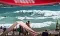 Surfers and beachgoers on a busy summers day