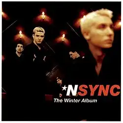 NSYNC members wearing black outfits while standing in a candle-lit room.