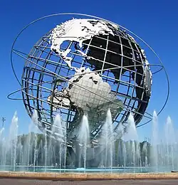 On a sunny day, in a pool with a fountains, sits a huge, skeletal representation of Earth, with North and South America visible.