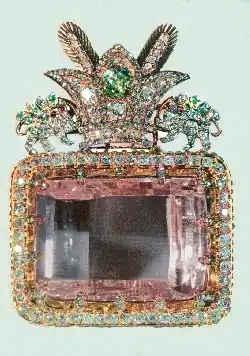 A large rectangular pink multifaceted gemstone, set in a decorative surround.